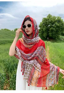Close-up of bohemian red ethnic shawl with frog button worn by model in field
