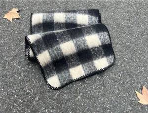 Detailed texture of a black and white checkered mohair scarf with whipped edges.