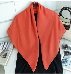 Close-up of coral orange solid color scarf draped on a black top with lifestyle accessories