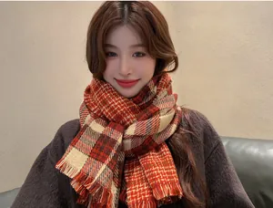 Close-up view of red and beige plaid knit scarf with fringe detail on an Asian model