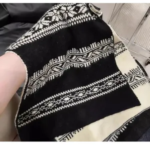 Dettaglio di una sciarpa in maglia jacquard Fair Isle bianca e nera con texture soffice.