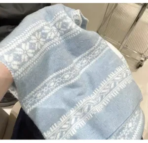 Dettaglio ravvicinato di sciarpa in maglia Fair Isle azzurra con fiocchi di neve