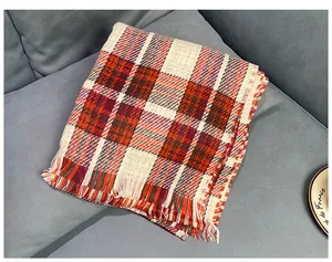Close-up of a retro British style red plaid winter scarf with fringe detail on a sofa