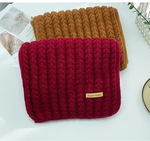 Detailed macro shot of burgundy and mustard ribbed knit scarves with a handmade tag.