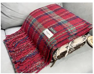 Close-up detail of folded red and green plaid faux cashmere scarf with fringe texture