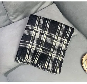 Close-up of a classic black and white plaid scarf with fringe detailed edge on a sofa