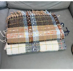 Close-up of two folded plaid cashmere-like winter scarves featuring tassel fringe details