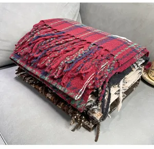 Close-up of stacked winter cashmere-like plaid scarves with tassels.