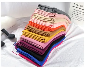 Detailed view of stacked solid color faux cashmere scarves in various autumn winter shades.