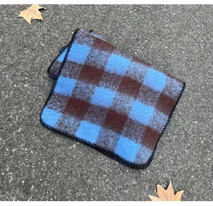 Detail view of a blue and brown checkered mohair scarf on an autumn asphalt background