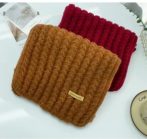 Close-up of thick knitted winter scarves in brown and red with a hand made label detail