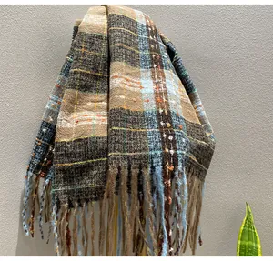 Close-up detail of soft winter plaid scarf fabric texture with stylish blue and brown fringe.