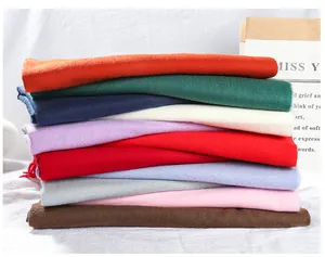 Close-up stack of colorful solid cashmere-like scarves showing texture and variety