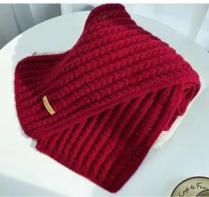 Detail shot of a thick Christmas red knitted scarf with a decorative hand made tag.