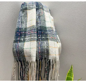 Detail view of a soft plaid scarf with fringe tassels and starry thread accents.