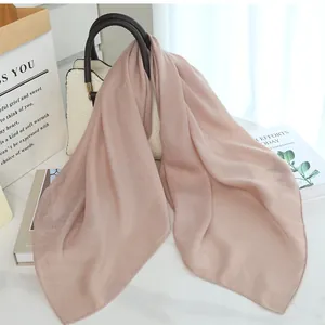 Elegant dusty rose solid color scarf elegantly draped over a white patterned handbag