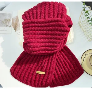 Detailed view of red cable knit scarf featuring a hand made tag on white background