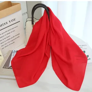 Bright red lightweight cotton linen scarf draped elegantly on a stylish handbag display