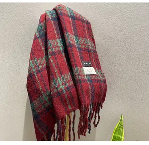 Detailed view of a thick red and green plaid winter shawl scarf with soft tassels