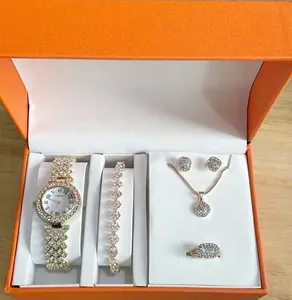 Detailopname van een luxe gouden dameshorloge- en sieradenset met strass in een oranje doos.