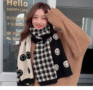 Close-up detail of a soft knitted black and white smiley face plaid scarf worn by a model
