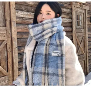 Detailed view of a blue plaid mohair scarf with brand label on a cozy winter outfit