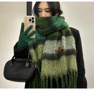 Close-up detail of green striped mohair scarf with soft texture and long fringe tassels.