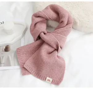 Detailopname van een zachte roze gebreide sjaal met decoratief label voor de winter