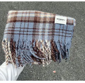 Close-up detail of a blue and brown plaid cashmere-like scarf with fringe and brand label