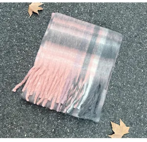 Soft mohair plaid scarf in pink and grey with tassels shown on autumn ground setting