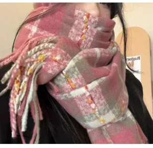Close-up detail of a soft pink plaid scarf with fringe, showing thick warm texture.