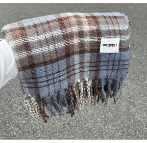 Macro detail of a thick blue and brown plaid scarf with tassels and a woven brand label