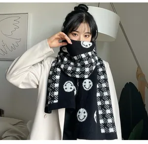 Detail view of thick black and white checkered knitted scarf with white smiley faces