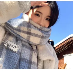 Close-up detail of blue and white plaid mohair scarf worn by a model in outdoor winter setting.