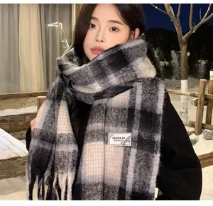 Cozy grey and white plaid mohair scarf with tassels worn in a winter snow scene.