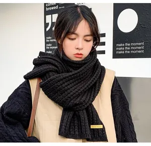 Dettaglio di una sciarpa in maglia nera pesante con etichetta 'hand made' in stile coreano alla moda.