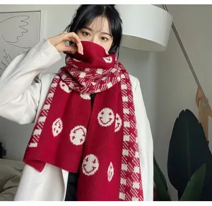 Detailed macro view of a cozy red knit scarf featuring white smiley faces and checkered patterns