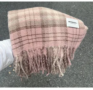 Close-up detail of a pink plaid faux cashmere scarf with soft fringe and brand label.