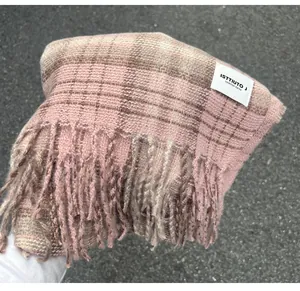 Detail view of a pink plaid scarf with fringe and brand label