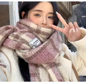 Detail view of a soft mohair plaid scarf in pink and beige worn by a model