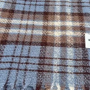 Close-up of a blue and brown plaid scarf showing soft cashmere-like weave texture