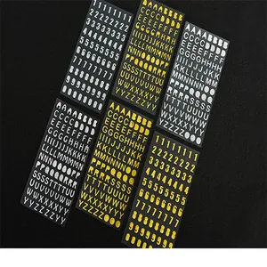 Vista macro detallada de pegatinas impermeables de letras y números en oro y blanco para bricolaje