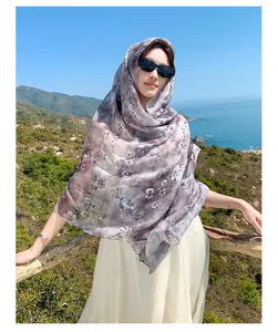 Elegant purple floral print Bali gauze shawl worn as a headscarf in scenic coastal setting
