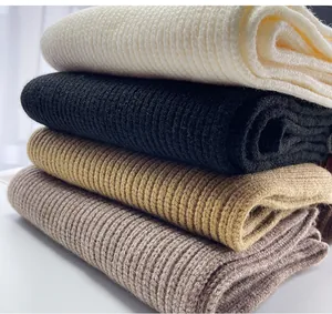 Dettaglio ravvicinato di sciarpe lavorate a maglia in bianco, nero e beige.