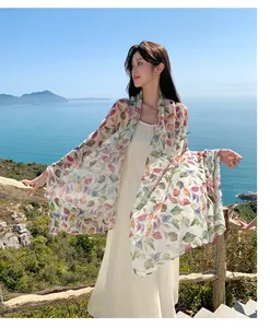 Macro view of colorful leaf printed sun protection shawl worn by model on sunny beach