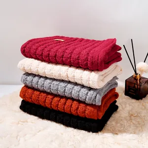 Cozy stack of solid color winter knitted scarves in multiple colors on a plush rug
