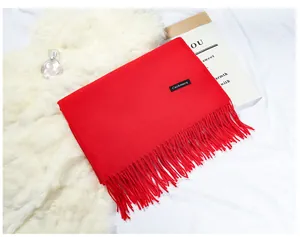 Detail view of a bright red cashmere-like winter scarf featuring elegant tassel fringe