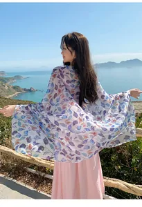 Elegant lightweight floral print sun-protection shawl worn by a woman at a scenic seaside overlook