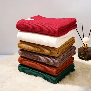 Pila di sciarpe a maglia spessa in tinta unita nei colori rosso bianco senape e verde