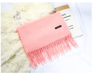 Detailed macro view of a soft pink cashmere-like scarf with elegant tassel fringe texture
